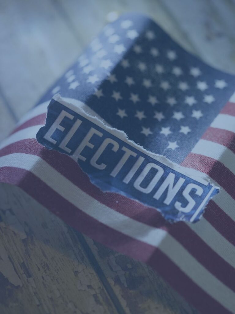 Paper American flag on table with word election ripped on top.