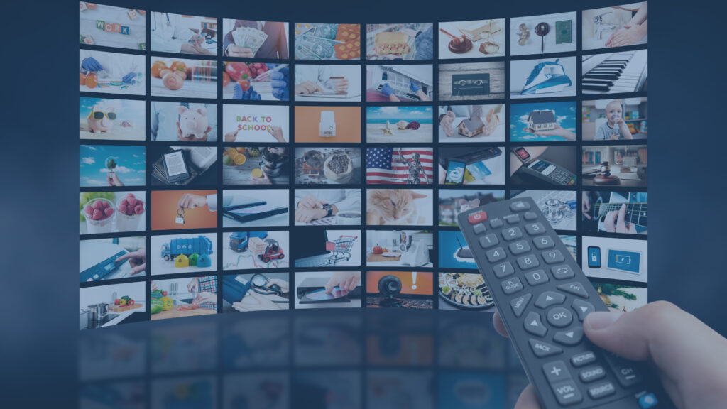 Person holding remote pointing at a wall of TVs.
