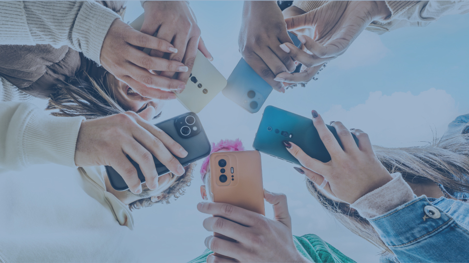 View of hands in a circle from below all holding cell phones.