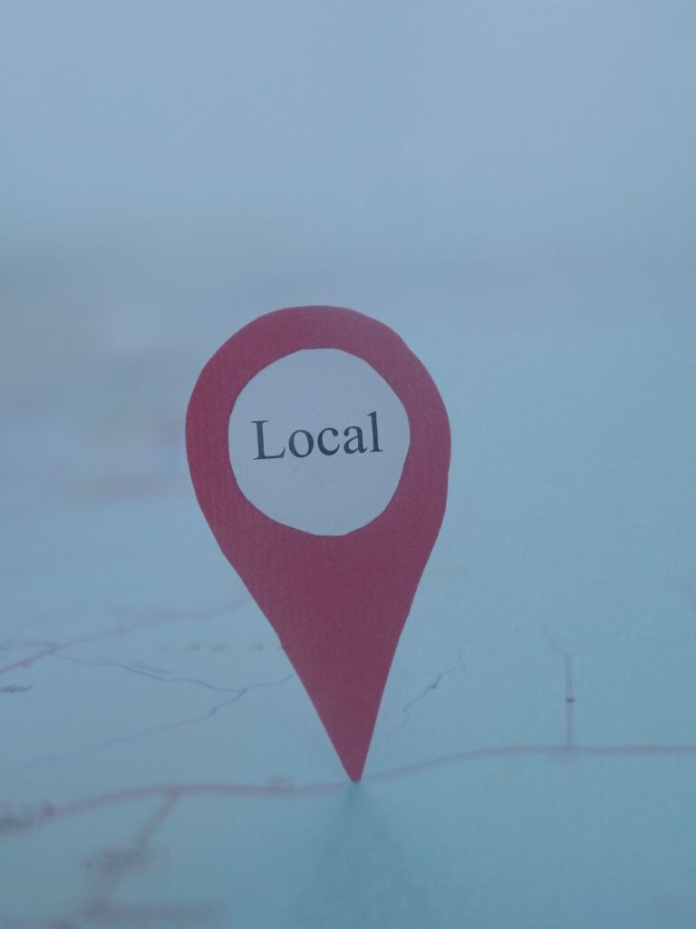 Pin with local written on it pointing to a map.