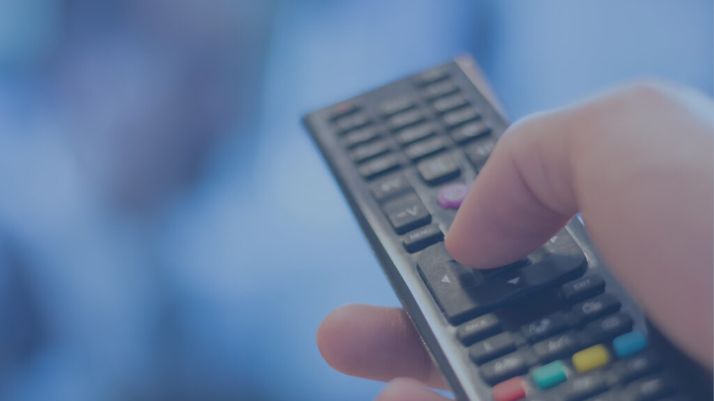 Hand holding a remote control for digital tv or streaming.