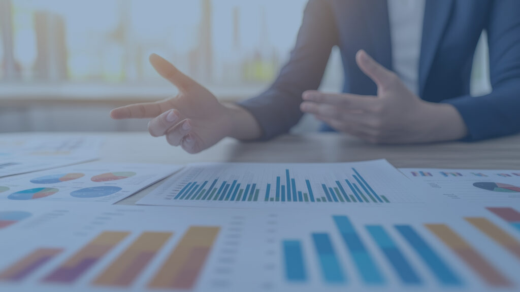 Hands of people who appear to be discussing graphs and charts on a table.